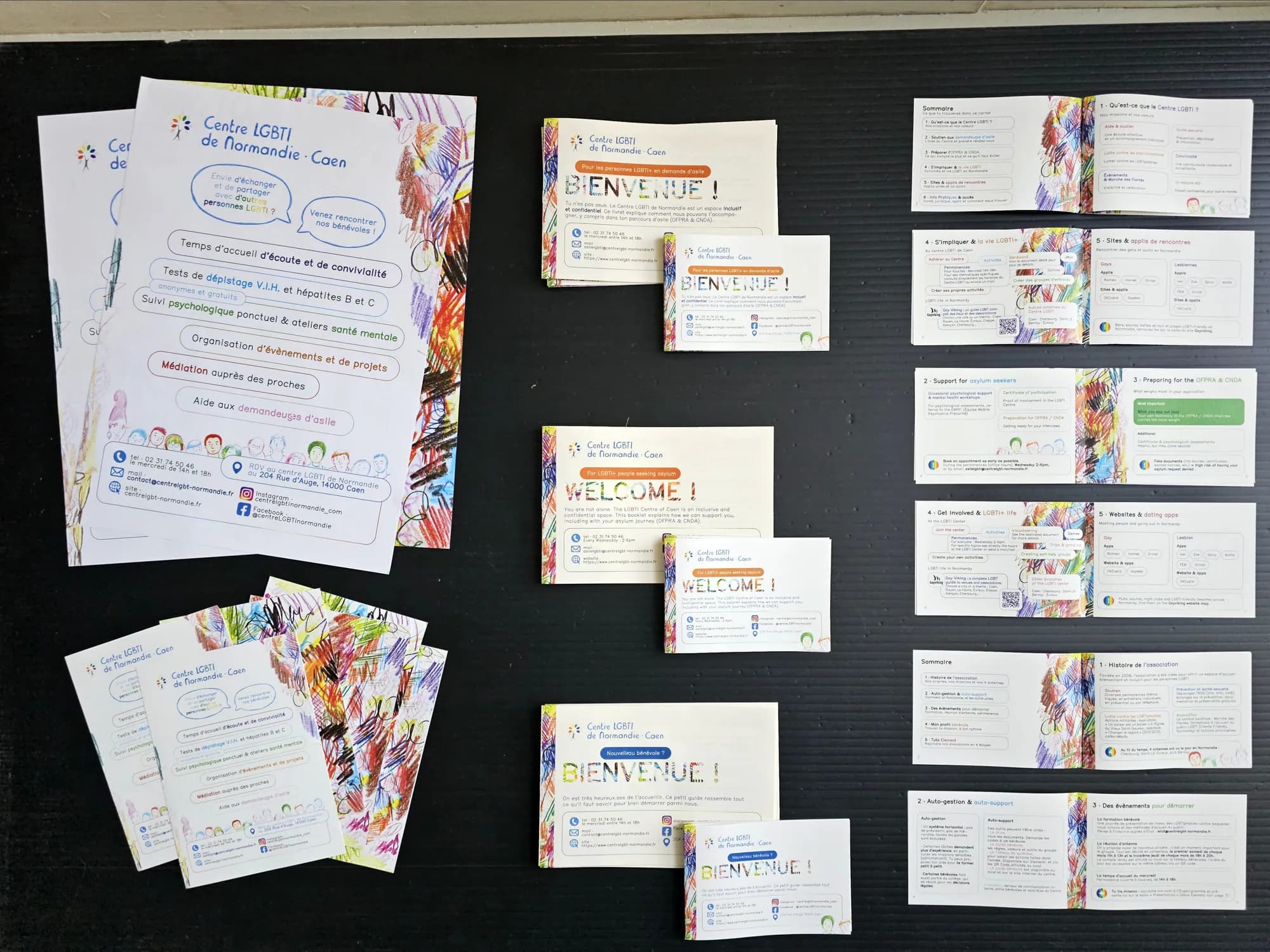 The resource kit for the Centre LGBTI de Normandie laid out on black: “Welcome!” and “Bienvenue !” booklets, cards and fact sheets