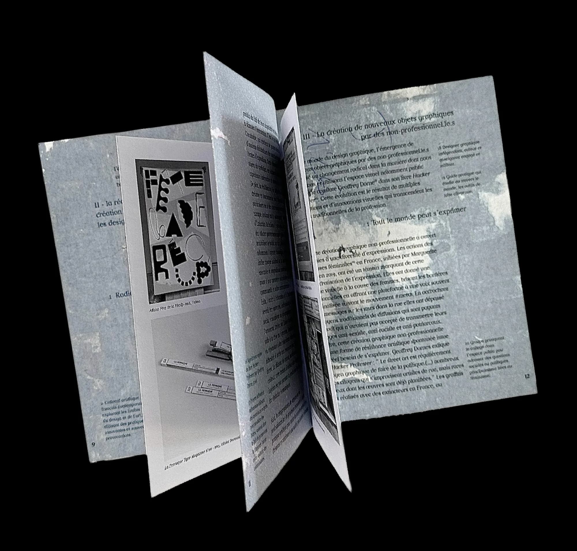 The thesis fanned open against black: pages with a textured blue ground, black text and images