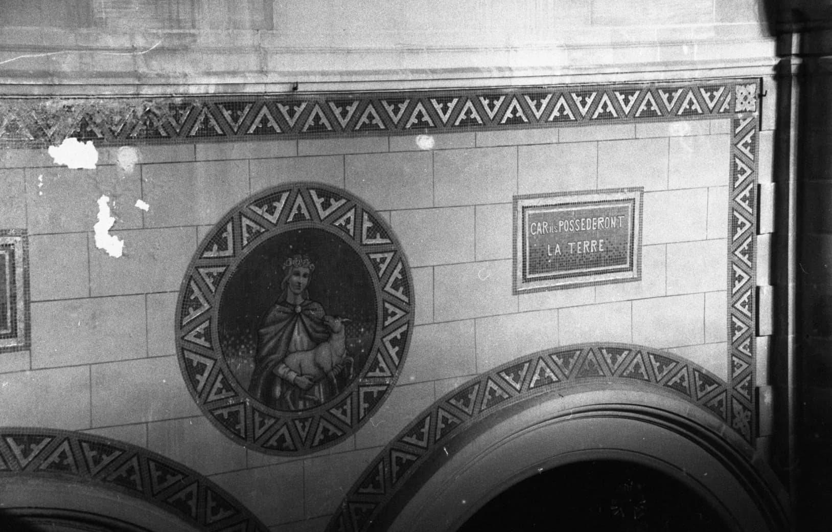 A mosaic medallion and a chevron frieze on a tiled wall, black and white